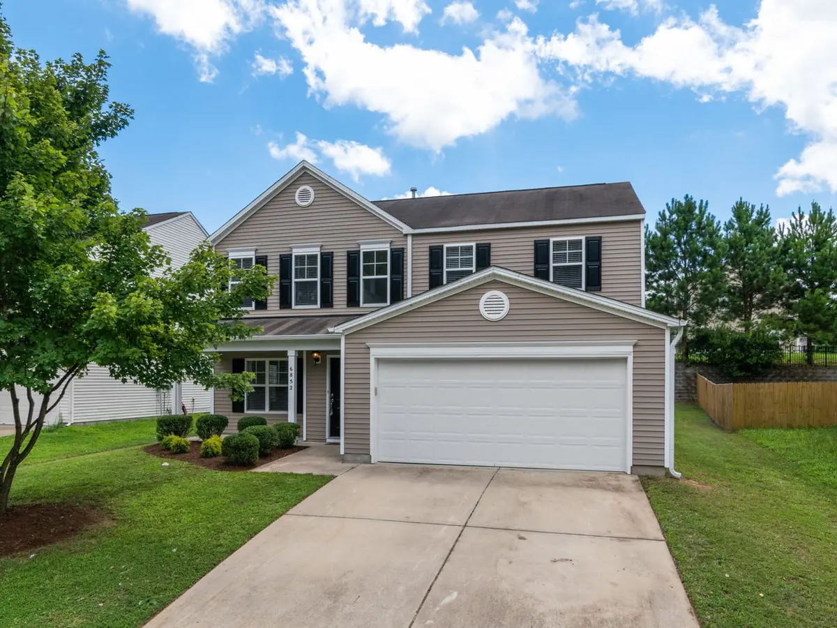 Two-story suburban home clad in tan lap siding, with black shutters and a white two-car garage door